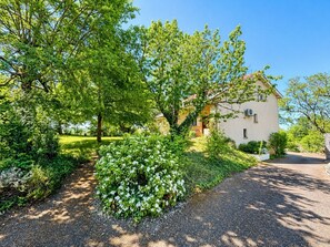 A house with a driveway, surrounded by lush greenery and trees. - Air-conditioned house with enclosed garden, 3 bedrooms, quiet location near Cahors (Pradines)