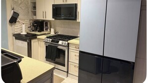 Eine Küche mit Herd, Mikrowelle, Backofen und einem Kühlschrank mit zwei Türen.