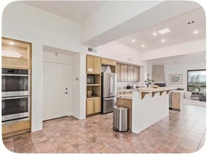 A modern kitchen with built-in appliances, a central island, and a dining area with a view. - Desert Escape in the Foothills!
Family friendly with pool and views (Tucson)