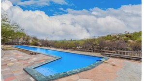 A swimming pool with a tiled deck, surrounded by a wooden fence and vegetation. - Desert Escape in the Foothills!
Family friendly with pool and views (Tucson)