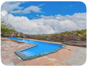 A swimming pool with a tiled deck, surrounded by a wooden fence and vegetation. - Desert Escape in the Foothills!
Family friendly with pool and views (Tucson)