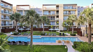 Ein Hotel mit mehreren Etagen, einem Schwimmbad und Außenbereichen zum Sitzen.