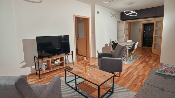 A modern living room with a flat-screen TV, a wooden coffee table, and grey sofas. - Gorgeous 3-bedroom apartment with 5-Balconies in the Center of Skopje (Skopje)