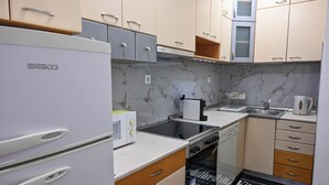 A compact kitchen with a white refrigerator, a microwave, a stove, and a dishwasher. - Gorgeous 3-bedroom apartment with 5-Balconies in the Center of Skopje (Skopje)