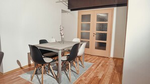 A dining area with a wooden table, black and white chairs, a vase with flowers, and a patterned rug. - Gorgeous 3-bedroom apartment with 5-Balconies in the Center of Skopje (Skopje)