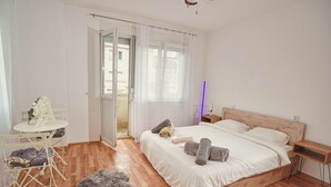 A bedroom with a wooden bed, white bedding, a small round table with chairs, and a fur rug on the floor. - Gorgeous 3-bedroom apartment with 5-Balconies in the Center of Skopje (Skopje)