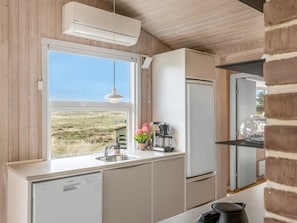 Eine moderne Küche mit Fenster, Spüle, Geschirrspüler, Kühlschrank und einer Pendelleuchte.