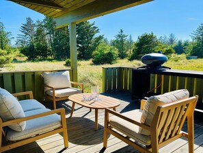Eine Terrass mit Gartenmöbeln, einem Grill und Blick auf einen Wald.