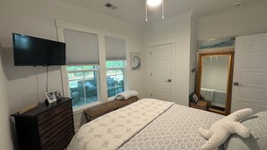 A bedroom with a bed, a bench, a dresser, a television, and a large mirror. - Newly built 2bed/2bath house on Dataw Island; TWO WEEK MINIMUM (Saint Helena Island)