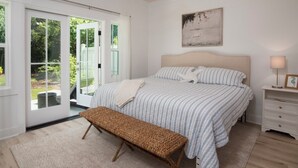 A bedroom with a bed, bench, bedside table, and a view through a glass door. - Newly built 2bed/2bath house on Dataw Island; TWO WEEK MINIMUM (Saint Helena Island)