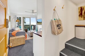 Ein modernes Interieur mit einer Couch, Korbmöbeln, einem Essbereich und Blick durch große Fenster.
