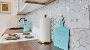 Una cocina con estufa blanca, cafetera color turquesa y un cartel que dice 'Kitchen Closed Gone to the Beach'.