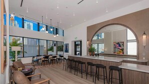 A modern bar area with high ceilings, large windows, and a central seating area with a bar counter.
