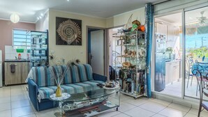 Ein Wohnzimmer mit einer Couch, einem Couchtisch und einer Glastür, die auf einen Balkon führt.