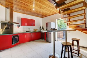 A modern kitchen with red cabinets, stainless steel appliances, and a wooden ceiling. - Kaz Bois Blanc- Vue mer - Avirons (Les Avirons)