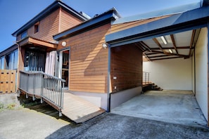 A two-story house with a wooden exterior, a covered garage, and a small outdoor deck. - Kaz Bois Blanc- Vue mer - Avirons (Les Avirons)