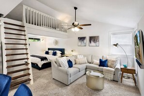 Ein modernes Schlafzimmer mit Bett, Sofa, Couchtisch und einer Treppe.