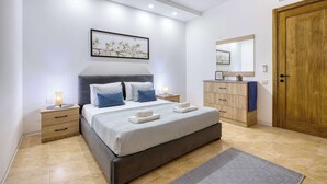 Ein modernes Schlafzimmer mit einem Bett, Nachttischen, einem Schminktisch, einer Kommode, einem Spiegel und einer Tür.