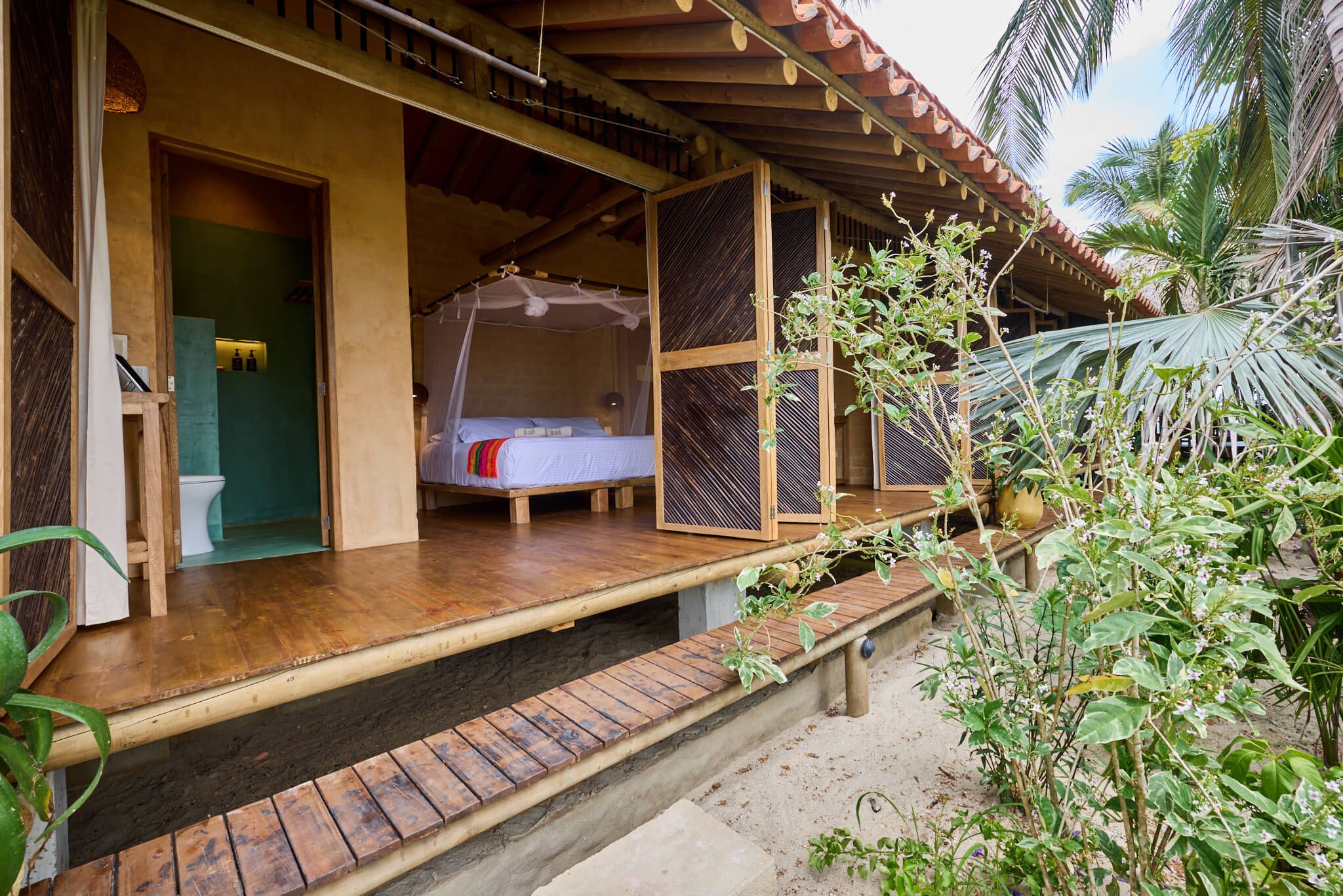 Estructura de madera con cama, inodoro y un espacio exterior techado.