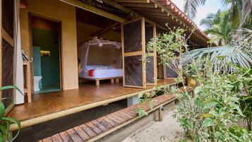 Estructura de madera con cama, inodoro y un espacio exterior techado.