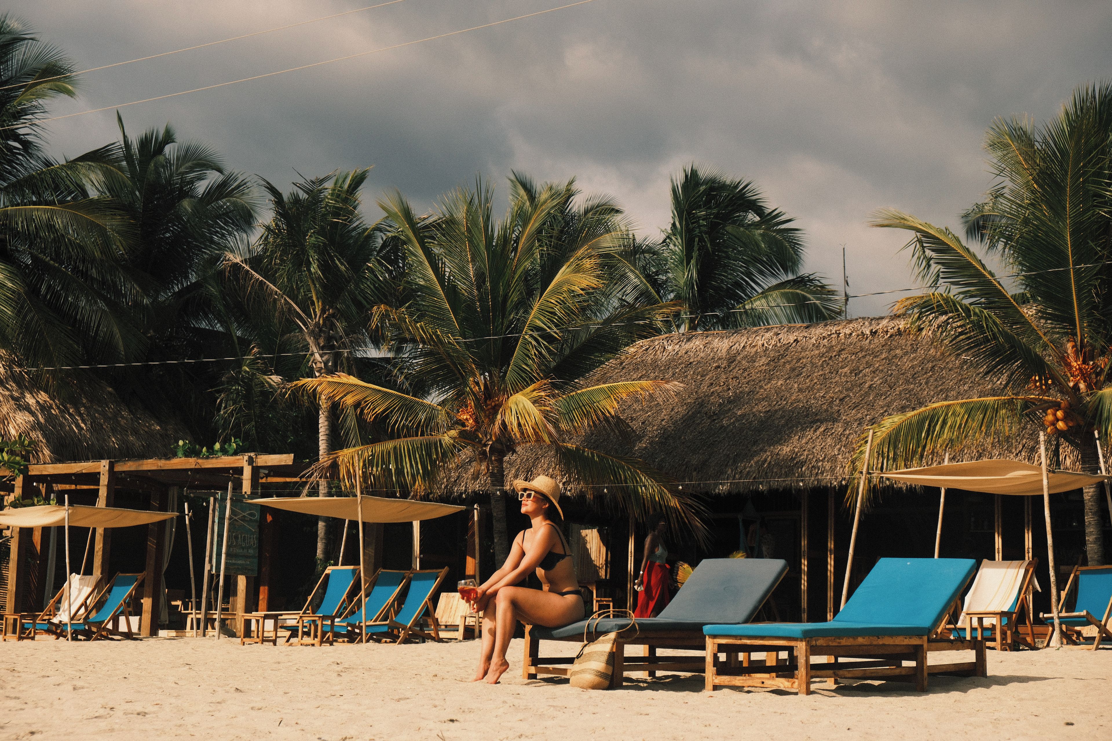 A beach with lounge chairs and a thatched-roof hut.