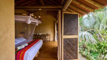 A room with two beds, a desk, and a view of a garden.
