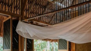 A room with a bed, a window with a view of greenery, and a wooden ceiling structure. - Dos Aguas Lodge (Rincón del Mar)