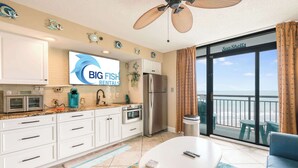 A modern kitchen with white cabinets, a stainless steel refrigerator, and a large window with a view of the sea. - Amazing 1Bedroom Unit with Amazing Oceanfront View (North Myrtle Beach)