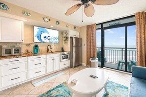 A modern kitchen with white cabinets, a stainless steel refrigerator, and a large window with a view of the sea. - Amazing 1Bedroom Unit with Amazing Oceanfront View (North Myrtle Beach)