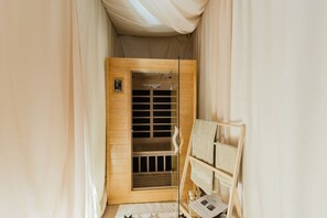 A narrow hallway with a wooden door, a small wooden bench with towels, and a sign on the door.