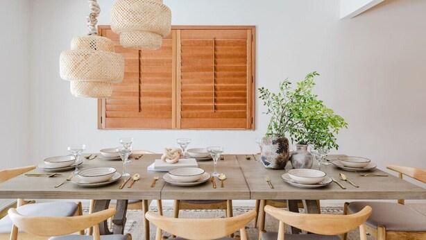 A dining area with a wooden table set for four, surrounded by wooden chairs, with a hanging light fixture above. - Waterfront Retreat | Pool, Game Room, Cinema & Spa (Hollywood)