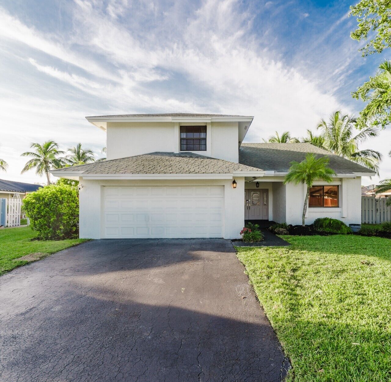 A single-story house with a garage, a front yard, and a palm tree.