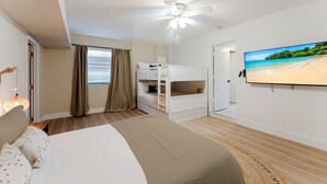 A bedroom with a bed, bunk beds, a ceiling fan, a TV, and a beach view. - Waterfront Retreat | Pool, Game Room, Cinema & Spa (Hollywood)