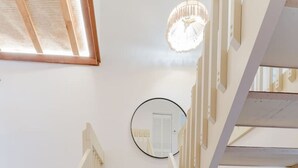 A staircase with wooden steps and white railings, a circular mirror on the wall, and a door at the bottom. - Waterfront Retreat | Pool, Game Room, Cinema & Spa (Hollywood)