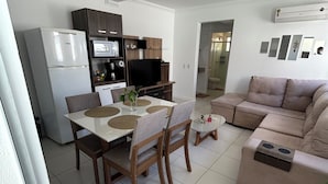 A modern kitchen with a dining area, a sofa, and a TV. - House just 5 minutes from the beach. (Florianópolis)