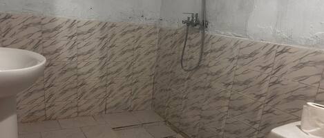 A bathroom with a toilet, a shower, and a sink.