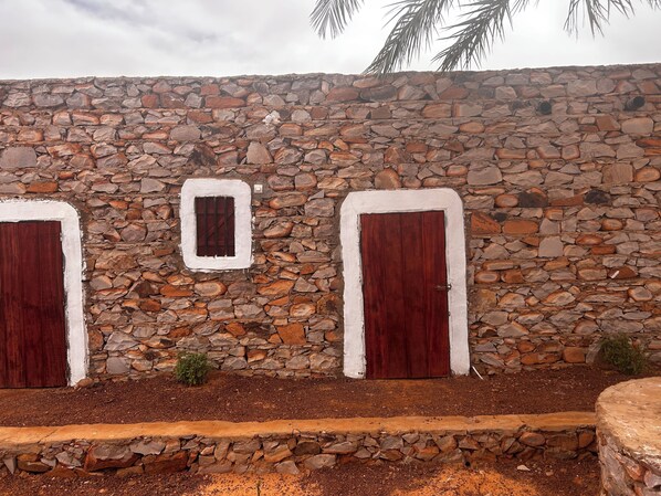 A stone wall with two wooden doors and a small window.