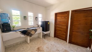 Una habitación con dispensador de agua, un refrigerador, una mesa con mantel y dos puertas de madera.