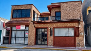 Un edificio de dos plantas con fachada de ladrillo, ventanas grandes y un escaparate visible con un cartel.