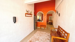 A hallway with a bench, a refrigerator, and a dining area with a table and chairs. - Casa Amaya (Isla Mujeres)