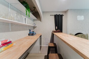 Una cocina compacta con encimeras de madera, una planta colgante y una ventana con cortina.