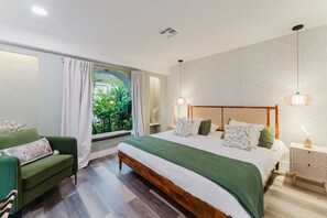 A bedroom with a large bed, a green sofa, a window with curtains, and a bedside table with a lamp. - Deluxe Waterfront Villa | BBQ, Pool and Game Room (West Palm Beach)