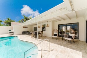 A pool area with a covered patio, outdoor seating, and a view of the sky. - Deluxe Waterfront Villa | BBQ, Pool and Game Room (West Palm Beach)