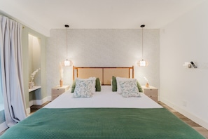 Un dormitorio con una cama grande, dos mesitas de noche, un cabecero de madera y lámparas colgantes.