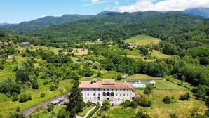 Un grand bâtiment doté d’une cour intérieure, entouré d’une végétation luxuriante et avec des collines en arrière-plan.