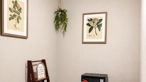 Una habitación con escritorio, silla, impresora, ilustraciones botánicas enmarcadas y una escalera de madera.