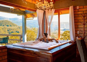A hot tub with a view of mountains, a wooden deck, and a chandelier. - Chalet 2 - Mountain Range: Design with Hot Tub in the Canyons - Comfort 7km from the Center (Praia Grande)
