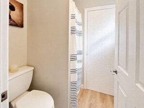 Een badkamer met een toilet, douchegordijn en een deur.