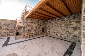 Um quarto com paredes de pedra, teto de madeira, piso de mármore e uma pequena janela.