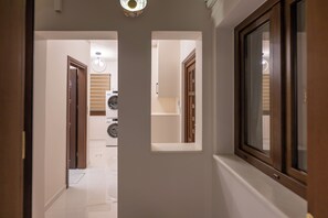Um corredor com máquina de lavar, uma porta e uma janela.